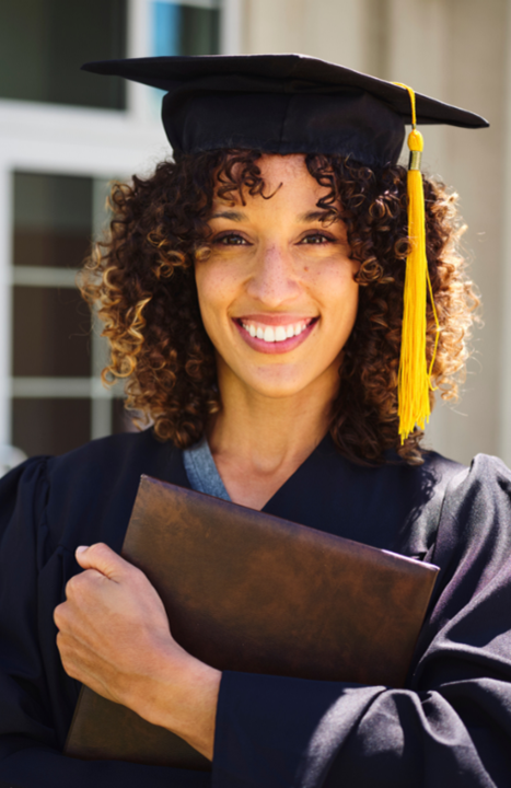 An adult, mixed-race woman wearing a graduation cap and gown and holding a diploma.